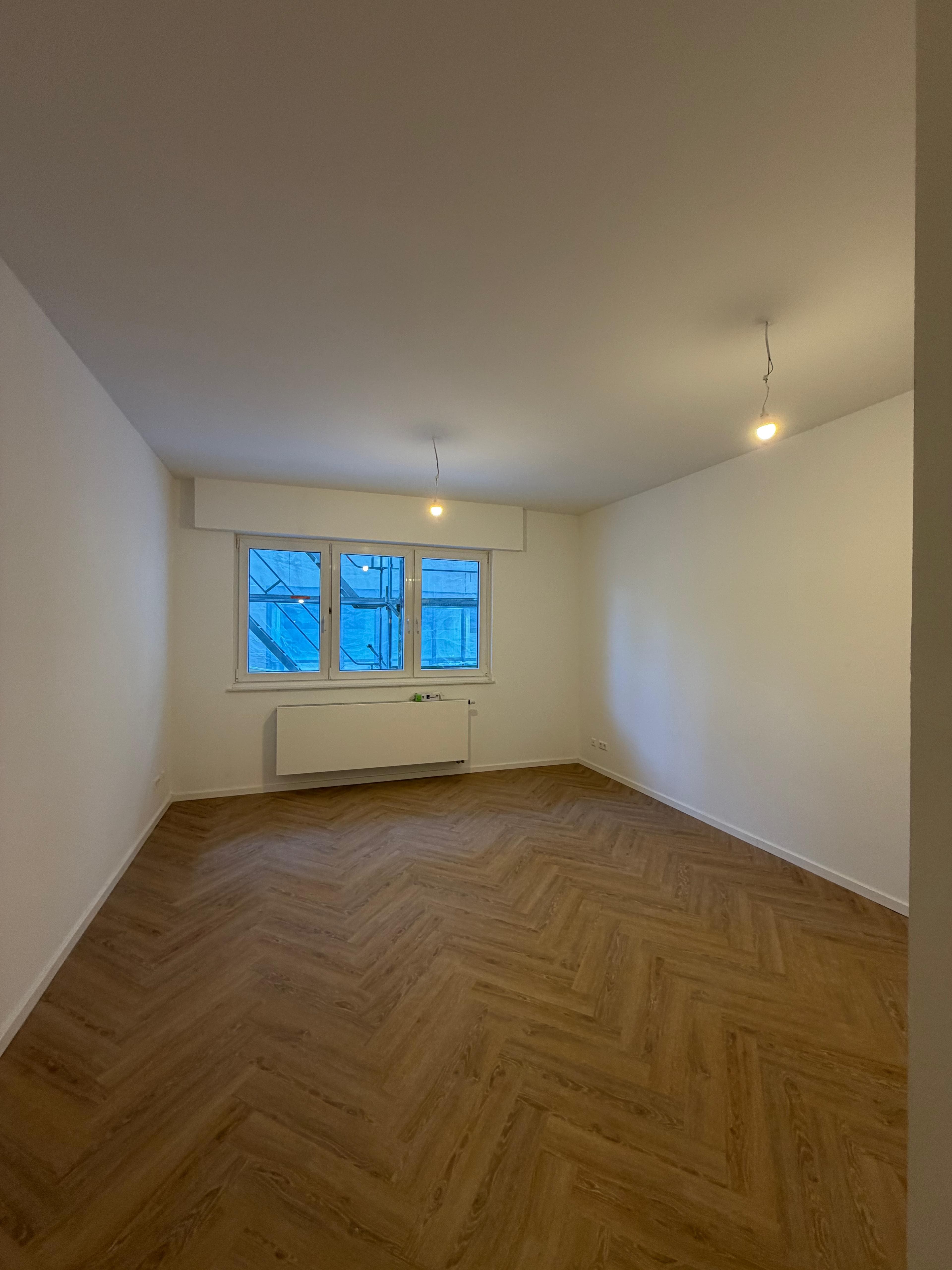Energetische Sanierung Kriegerstraße, Stuttgart – saniertes Zimmer mit neuem Boden und Heizkörper